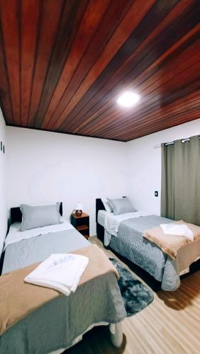a room with two beds and a wooden ceiling at Cantinho Dona Cleide in Monte Verde