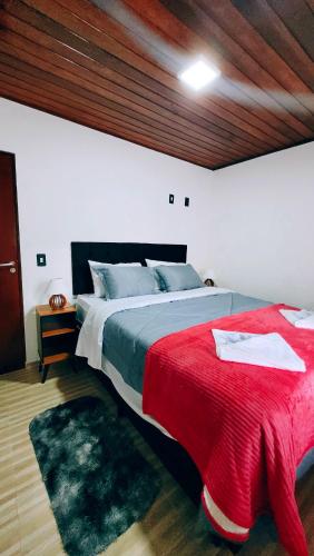 a bedroom with a large bed with a red blanket at Cantinho Dona Cleide in Monte Verde