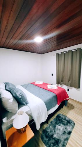 a bedroom with a large bed and a table at Cantinho Dona Cleide in Monte Verde
