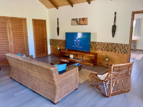 ein Wohnzimmer mit Korbmöbeln und einem Flachbild-TV in der Unterkunft Holiday house Nuupure - Accès plage privée & terrain de Pickelball in Maatea