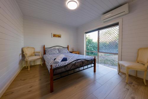 a bedroom with a bed and two chairs and a window at caplesound stays in Capel Sound