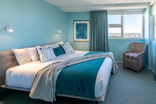 ムールーラバにある84 The Spit Holiday Apartmentsの青いベッドルーム(大型ベッド1台、椅子付)