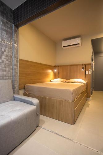 a bedroom with a large bed and a couch at Studio Barra Concept in Salvador