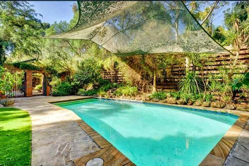 a swimming pool in a yard with an umbrella at Granny Unit Self Contained Double Storage WIFI POOL PARKING in Templestowe