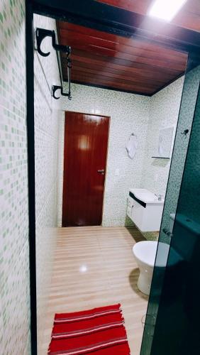 a bathroom with a toilet and a red door at Cantinho Dona Cleide in Monte Verde
