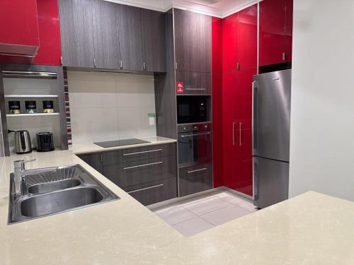 a kitchen with stainless steel appliances and red cabinets at Elsey on Parap in Darwin