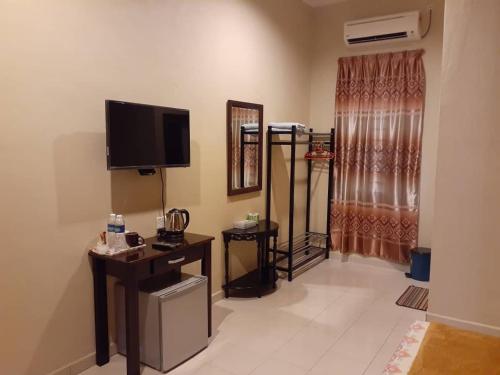 a living room with a flat screen tv on the wall at Four F Motel by Lily in Pantai Cenang