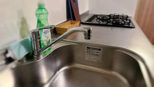 a kitchen sink with a green bottle of detergent on it at Rakuyado Shinimamiya in Osaka