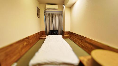 a small room with a bed and a window at Rakuyado Shinimamiya in Osaka
