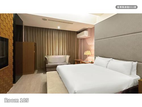 a hotel room with a white bed and a chair at Milan Motel in Miaoli
