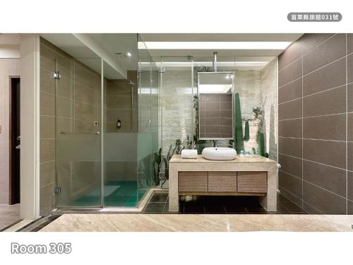 a bathroom with a glass shower and a sink at Milan Motel in Miaoli