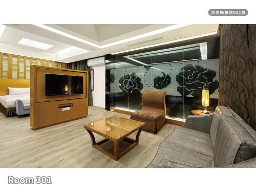 a living room with a couch and a tv and a bed at Milan Motel in Miaoli