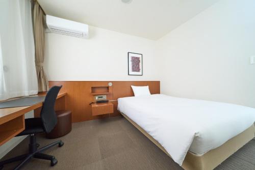 a bedroom with a bed and a desk and a computer at Hotel Tohkai in Atsugi