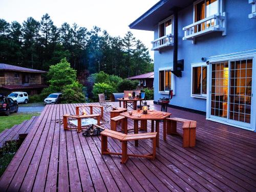 a wooden deck with picnic tables and benches on a house at Stella八ヶ岳原村-星空,サウナ,BBQ,大型スクリーンを楽しめる八ヶ岳の貸切宿 in Hara