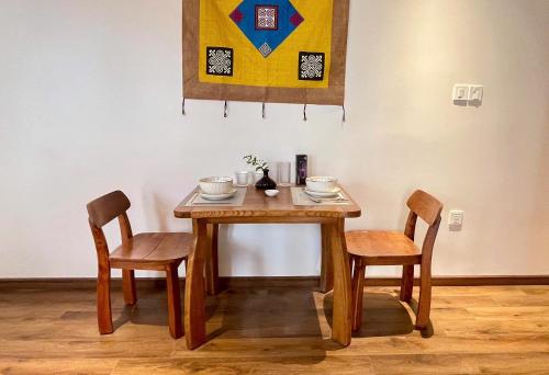 a wooden table with two chairs and a table with cups at Kim House Boutique Hotel Da Nang in Da Nang