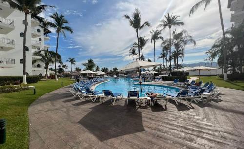 a resort pool with chairs and umbrellas and palm trees at Villa Marina in Puerto Vallarta