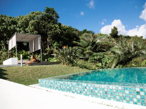 a woman is sitting next to a swimming pool at Jusandi in Ishigaki Island