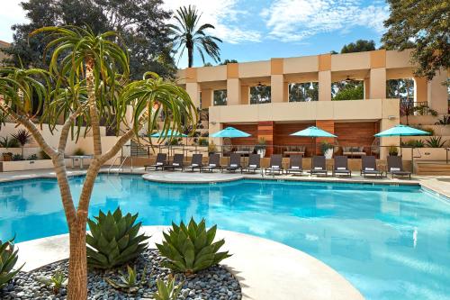 a pool with chairs and palm trees in front of a hotel at San Diego Marriott Mission Valley in San Diego