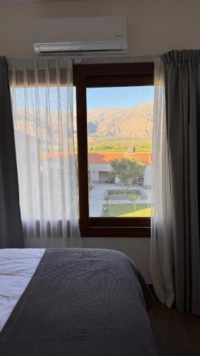a bedroom with a bed and a window with a view at Vista Montañas y Viñas in Cafayate