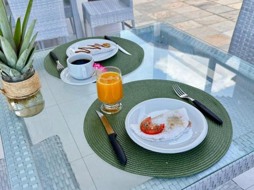 a table with two plates of food and a glass of orange juice at Caly Pousada in São Miguel do Gostoso