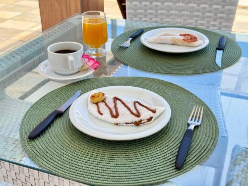 two plates of food on a table with a cup of coffee at Caly Pousada in São Miguel do Gostoso