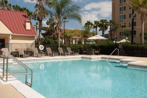 a swimming pool with chairs and a building and palm trees at Residence Inn Orlando Convention Center in Orlando