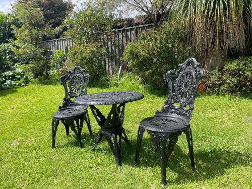 two black chairs and a table in the grass at Garden View Entire Self Contained Guesthouse in Engadine