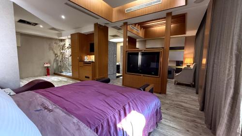 a bedroom with a purple bed and a flat screen tv at Milan Motel in Miaoli