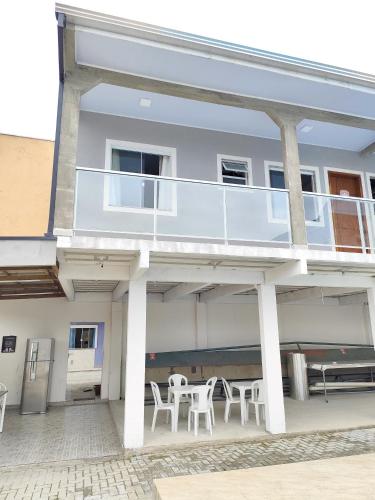 a house with a balcony with white tables and chairs at Apartamento kit aconchegante 3 in Matinhos