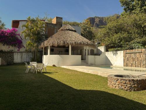 a house with a yard with a pool and a building with a thatch roof at Habitacion Cerca del centro 1 in Tepoztlán