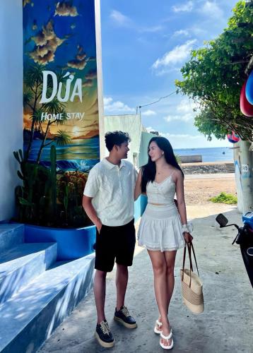 a man and a woman standing in front of a sign at Dứa Homestay in Cu Lao Thu