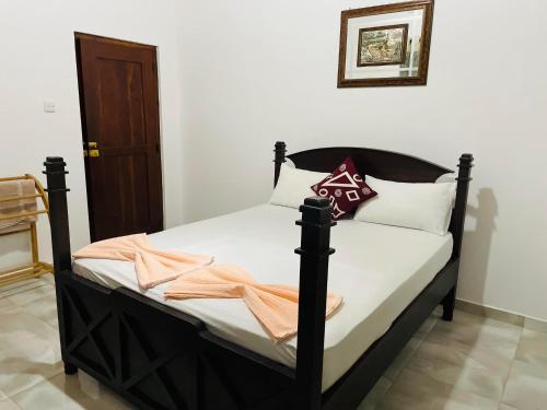 a bedroom with a black bed with white sheets and pillows at Suzukis lagoon front in Katunayake