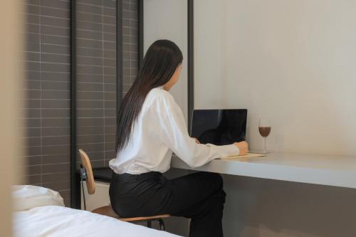 a woman sitting at a desk with a laptop at Hotel Yaja Siheung Jeongwang in Siheung