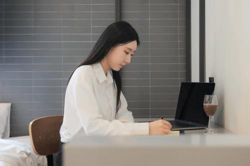 a woman sitting at a table with a laptop at Hotel Yaja Siheung Jeongwang in Siheung