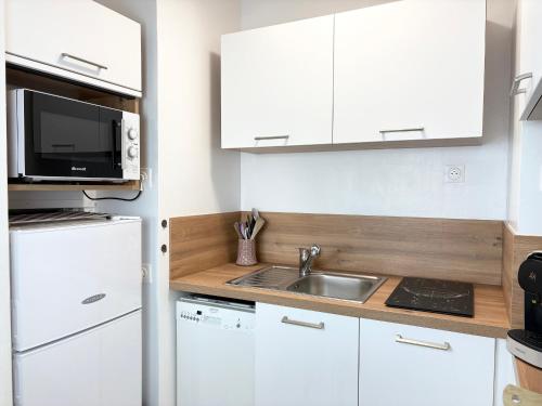 une cuisine blanche avec un évier et un micro-ondes dans l'établissement Appartement face océan pour 4/6 personnes avec accès direct à la plage et parking privé - FR-1-323-516, à Saint-Hilaire-de-Riez