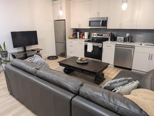 a living room with a leather couch and a kitchen at Beautiful 2 Bedroom suite in White Rock
