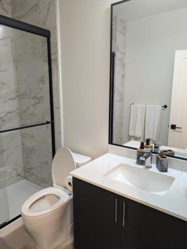 a bathroom with a toilet and a sink and a shower at Beautiful 2 Bedroom suite in White Rock