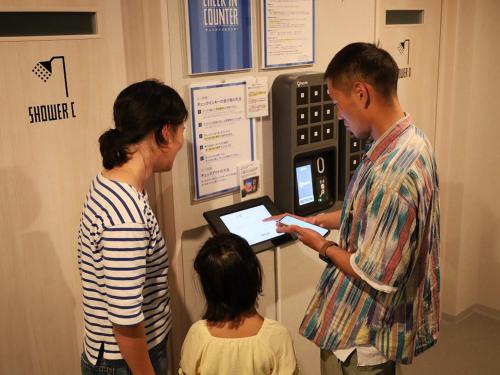 a man and woman looking at a display with a child at Sakatanto Container Hotel CAMPS in Sakata