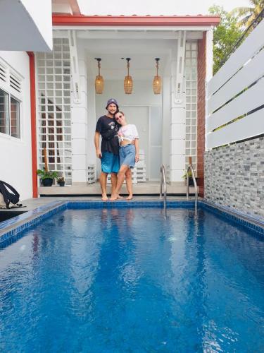 a man and a woman standing next to a swimming pool at Lanka Villa Mirissa in Mirissa