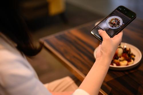 a person taking a picture of a bowl of food at The Royal Park Canvas - Osaka Kitahama in Osaka