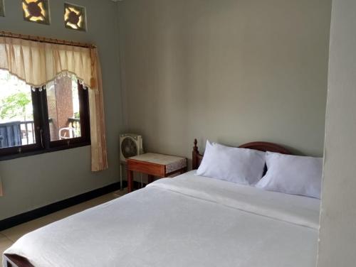 a bedroom with a white bed and a window at ESTEVANIA LODGE Kelimutu in Ende
