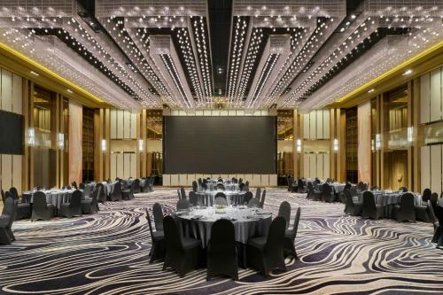 a ballroom with tables and chairs and a projection screen at JW Marriott Hotel and Suites Saigon in Ho Chi Minh City