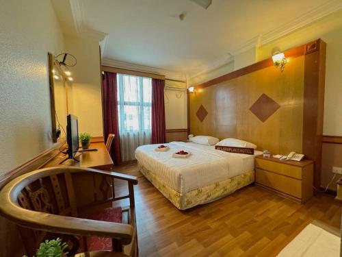 a hotel room with a bed and a television at Flora Place Hotel in Kota Bharu