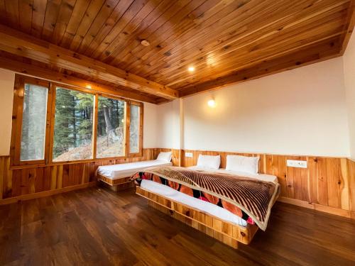 two beds in a room with wooden walls at Singing Woods Kutla in Kulu