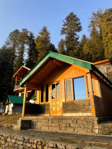 a small wooden house with a green roof at Singing Woods Kutla in Kulu
