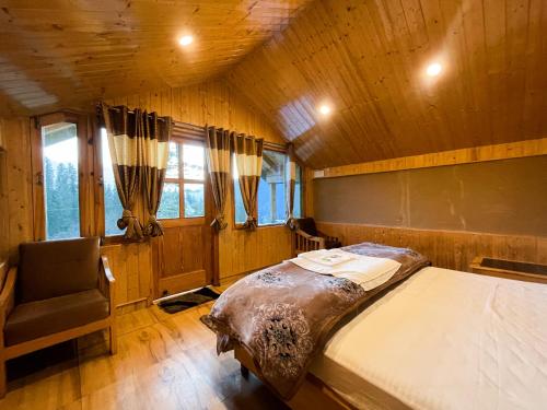a bedroom with a bed and a chair in a cabin at Singing Woods Kutla in Kulu