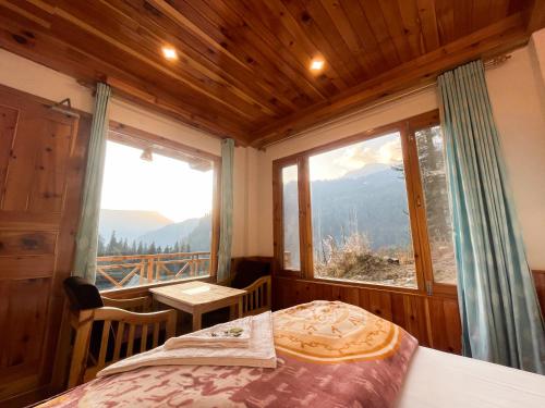 a bedroom with a bed and a large window at Singing Woods Kutla in Kulu