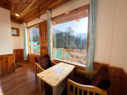a dining room with a table and a large window at Singing Woods Kutla in Kulu
