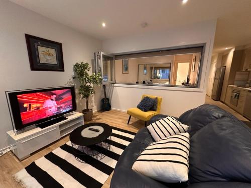 a living room with a couch and a flat screen tv at A Cozy apartment to yourself in Canberra