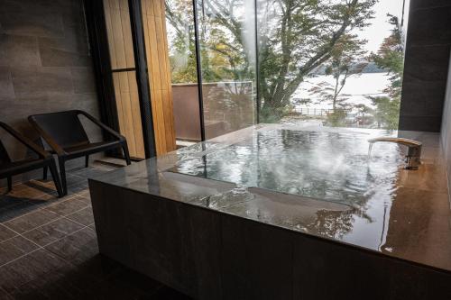 a bath tub with a sink and a window at Haku Fuji Yamanakako in Yamanakako